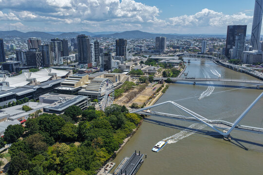 Aerial view of the Brisbane River featuring the Neville Bonner Bridge, the Wheel of Brisbane, and the South Bank Cultural Forecourt amidst the city skyline in Brisbane, Queensland, Australia.