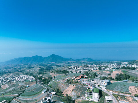 Aerial view of Nepal Van Java, a village on the slopes of Mount Sumbing with terraced fields, houses, and distant mountains in Kecamatan Kaliangkrik, Jawa Tengah, Indonesia.