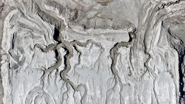Aerial view of a sand quarry showing intricate erosion patterns and heavy machinery tire tracks across the textured ground in St. Johns County, Florida, United States.