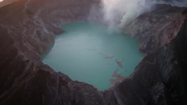 Turquoise acidic crater lake inside volcanic caldera with fumaroles and steep rocky walls at sunrise.