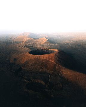 Aerial view of the volcanic crater of Fuerteventura with rugged terrain, dramatic shadows, and arid landscape in Las Palmas, Canary Islands, Spain.