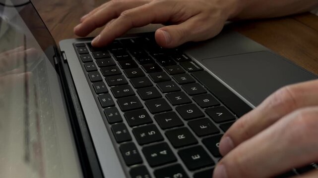 Finger holding delete key to erase typed text on laptop keyboard, correcting mistake concept, low angle close up