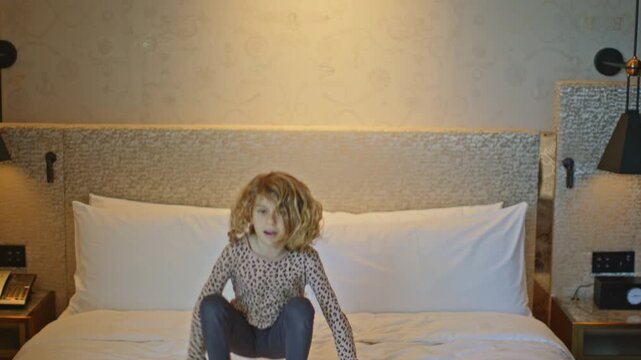 small kid jumping on hotel bed 