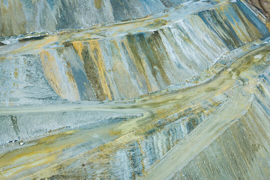 Aerial view of the Bingham Copper Mine showing the terraced open-pit landscape with exposed rock layers and winding haul roads in Salt Lake County, Utah, United States.