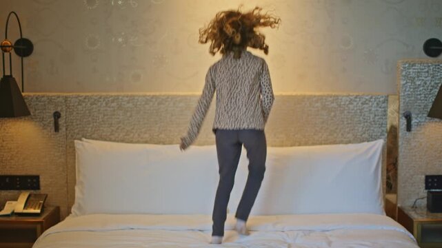 small kid jumping on hotel bed 