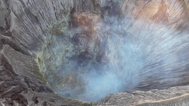 Sulfurous steam and sunset glow rising from Mount Bromo crater textured volcanic rock walls.