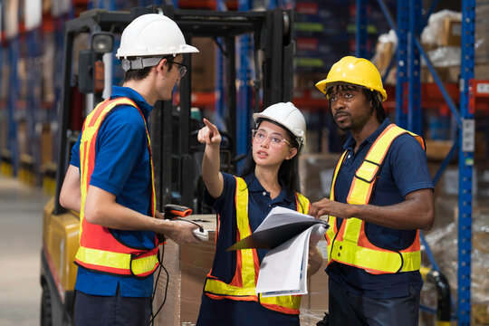 Warehouse workers, warehouse storage and logistics. Professional multiethnic team of warehouse workers discussing logistics plan and checking stock control while working in storage warehouse