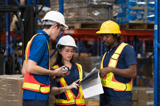 Warehouse workers, warehouse storage and logistics. Professional multiethnic team of warehouse workers discussing logistics plan and checking stock control while working in storage warehouse