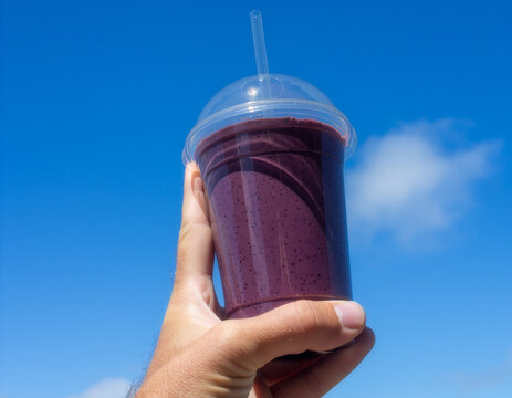 Clear purple smoothie cup mockup held against blue sky