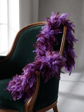 Luxurious purple feather boa draped on vintage velvet chair  