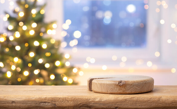 Empty wooden podium on table with blurred Christmas tree and festive golden lights in background