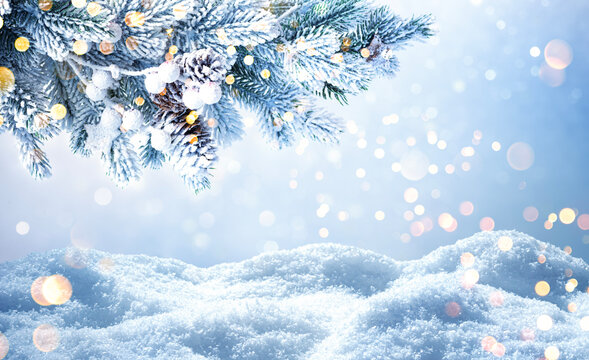 Snowy winter landscape with frosted pine branches and blurred festive lights