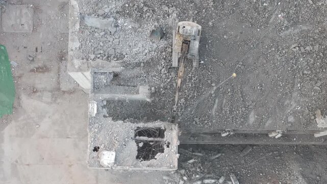 Excavator with hydraulic hammer dismantling a building at a construction site