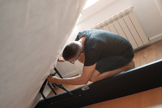man adjusting the mechanism of a storage bed