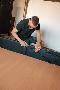 man using a ratchet on a lift-up storage bed