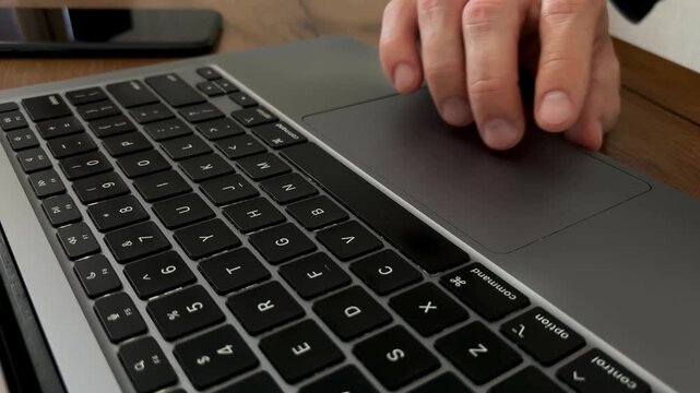 Hand using laptop touchpad with finger swipe, scroll and multi touch gestures, close up of trackpad and keyboard