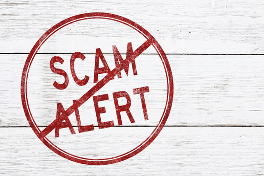 Red distressed Scam Alert stamp on weathered wood for warning
