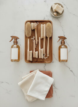 Top view flat lay of eco friendly wooden cleaning brushes and amber glass spray bottles on marble background