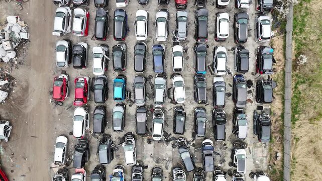 Aerial view of a densely packed car junkyard with rows of dismantled vehicles, showcasing various colors and models, highlighting the extensive collection of auto parts and scrap materials