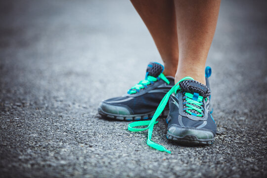 Running Shoes With Untied Laces on Pavement