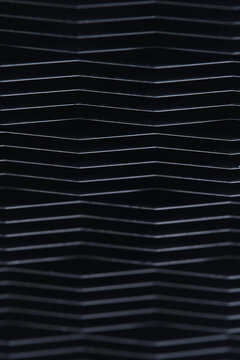 Vertical macro composition repeating black metal geometric lines and dark shadows.