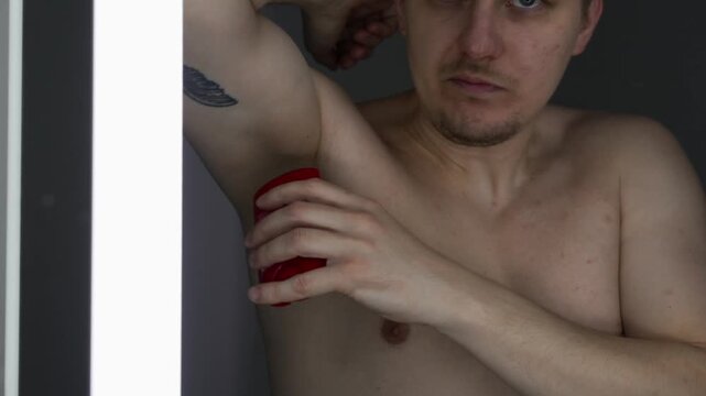 A man applies a gel antiperspirant to his underarms to protect against unpleasant odor.
Beauty routines in the bathroom