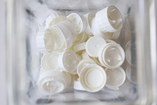 White plastic bottle caps gathered inside a transparent container