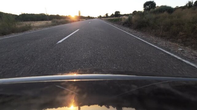 Driving Toward Blinding Sunset on a Rural Asphalt Road