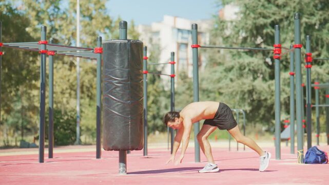 Man performs a controlled handstand against a padded pole during outdoor calisthenics training at a sunny workout park.