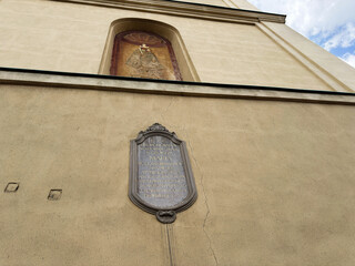 Historic church exterior with commemorative plaque and faded mural above textured plaster wall in Rzeszow Poland © AS Photo Family