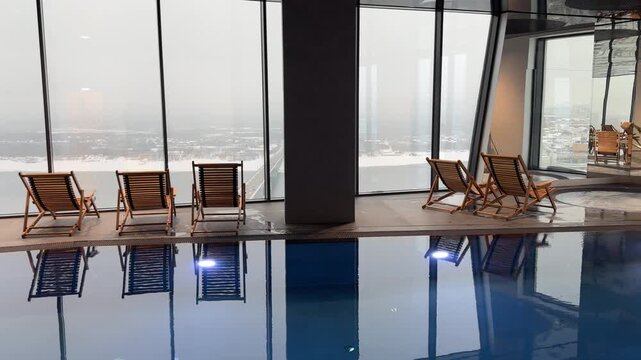 Wooden loungers by a spa pool with panoramic windows, blending indoor comfort and outdoor serenity for ultimate relaxation.