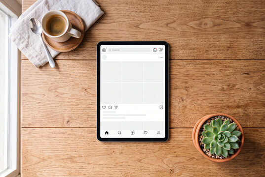 Blank tablet screen social media interface flat lay mockup on wooden table with coffee and succulent, content creator lifestyle scene for social media brand and digital marketing