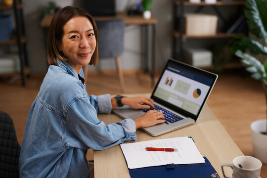 Asian woman working remotely at a laptop in a home office