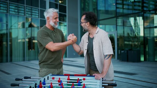 Mature male friends playing table football and enjoying social time together.