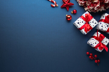 Merry Christmas and Happy Holidays greeting card, frame, banner. New Year. Red Christmas ornaments and gifts, presents on blue background top view. Xmas holiday festive theme. Christmas decoration.