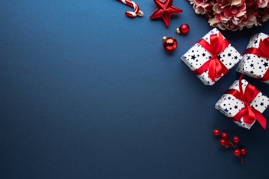Merry Christmas and Happy Holidays greeting card, frame, banner. New Year. Red Christmas ornaments and gifts, presents on blue background top view. Xmas holiday festive theme. Christmas decoration.