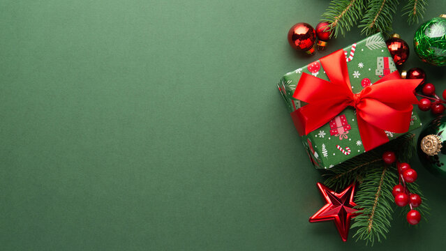 Green Christmas and Happy New Year holiday background with gift boxes, red ribbon bows and festive red ornaments, flat lay with copy space. Greeting card.