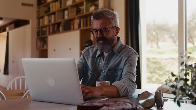 Man working from home office, drinking coffe and working on laptop.