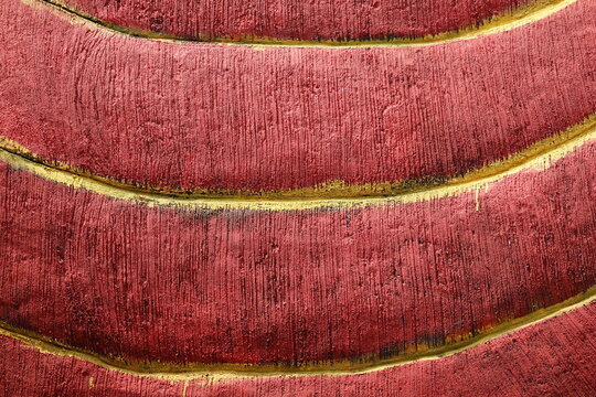Rough maroon painted cement wall creates a unique decorative textured background surface.