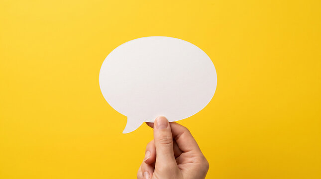 Human hand holding one blank white speech bubble, yellow background, clean modern advertising aesthetic. Communication concept. Mock-up. Close-up.