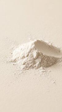 Small mound of white powder on ivory matte surface. Close-up.