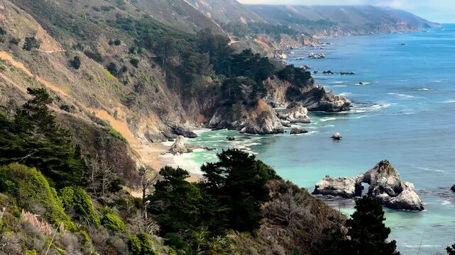 Rocky coastal cliffs with turquoise sea and natural rock arch - Cabrillo Highway, California, United States