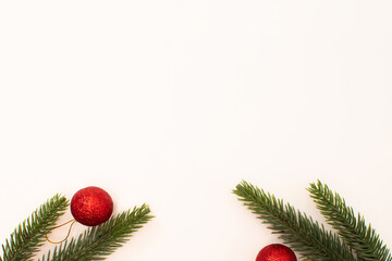 Miniature red Christmas ornament balls with pine tree branches on a white background. Seasonal greetings and holiday design layouts. © Maja 