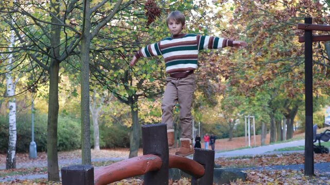 Cute blond child in the park, playing with knitted pumpkins, autumn time