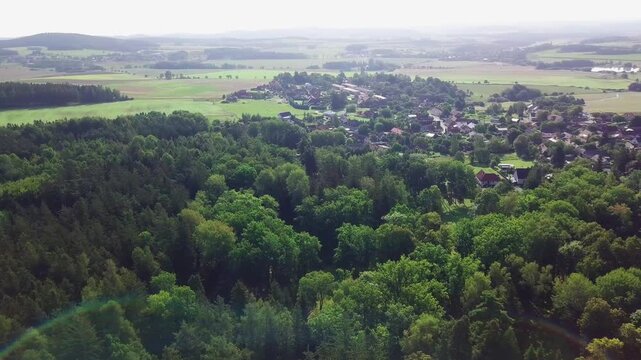 Aerial flight toward the village of Vysok&aacute; u Př&iacute;bramě among trees with fields and hills beyond and forest in the foreground, Central Bohemia, Czech Republic.