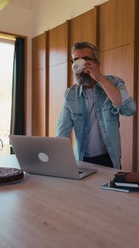 Man working from home office, drinking coffe and working on laptop.