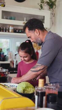 Dad and daughter making breakfast in kitchen.