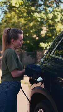 Woman charging electric car before trip.