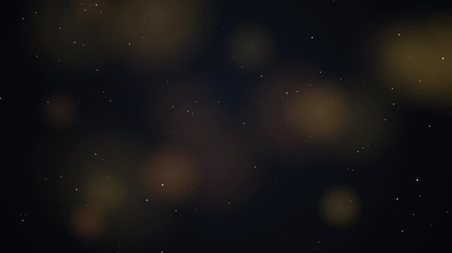 Golden bokeh lights and shimmering particles move on dark background