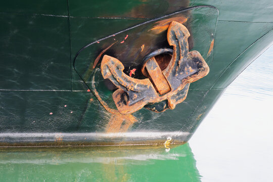 Rusted anchor against a dark green ship hull
